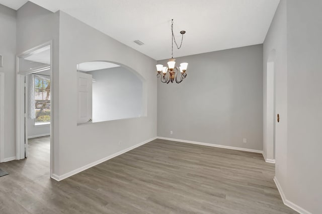 spare room with an inviting chandelier and hardwood / wood-style floors