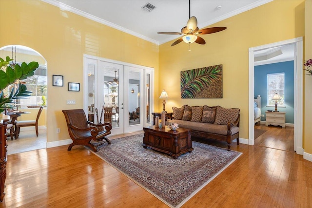 living area featuring visible vents, wood-type flooring, ceiling fan, and ornamental molding