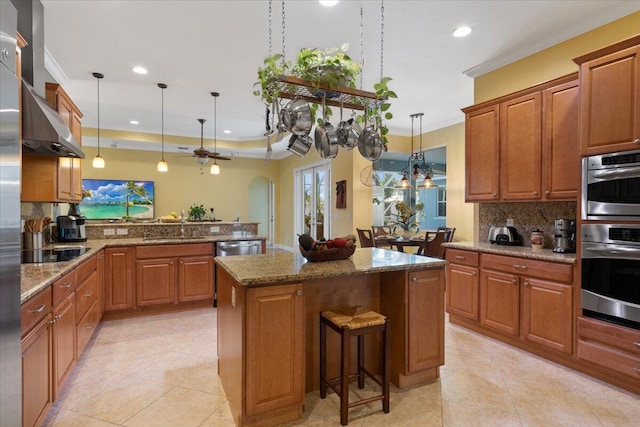 kitchen with a breakfast bar, a center island, hanging light fixtures, kitchen peninsula, and stainless steel appliances