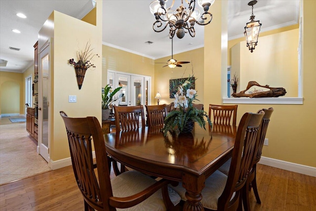 dining room featuring baseboards, visible vents, light wood finished floors, ornamental molding, and french doors