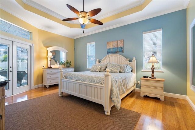 bedroom with french doors, crown molding, light hardwood / wood-style flooring, access to outside, and a raised ceiling