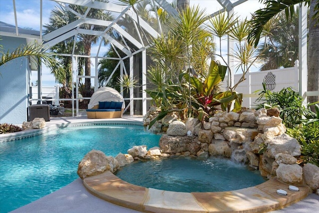 view of pool with glass enclosure, fence, and a pool with connected hot tub