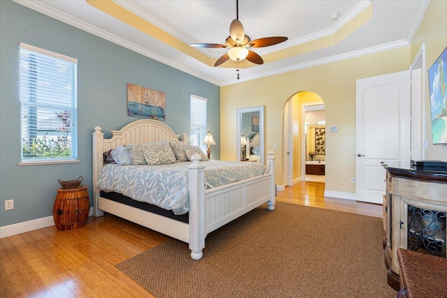 bedroom featuring ornamental molding, a raised ceiling, ceiling fan, and light wood-type flooring