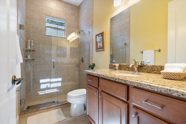 bathroom featuring tile patterned floors, vanity, toilet, and a shower stall