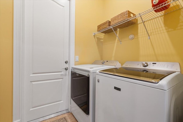 laundry area with washing machine and dryer and light tile patterned floors