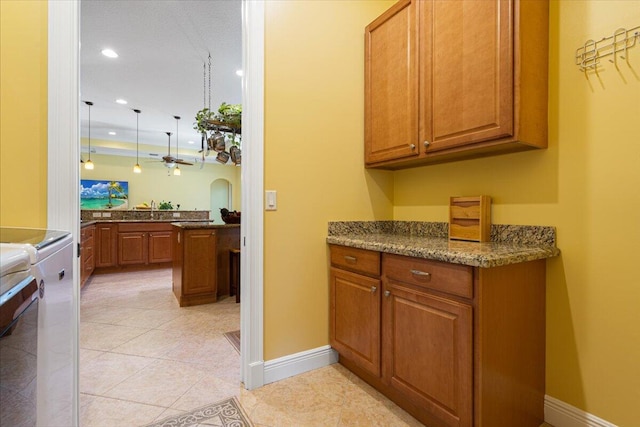 kitchen with brown cabinets, recessed lighting, range, light tile patterned flooring, and baseboards