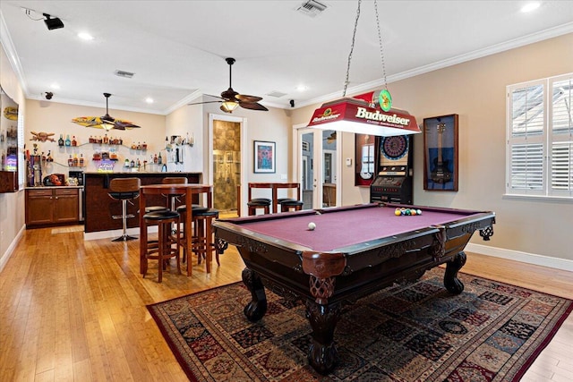 recreation room with crown molding, ceiling fan, bar, pool table, and light wood-type flooring