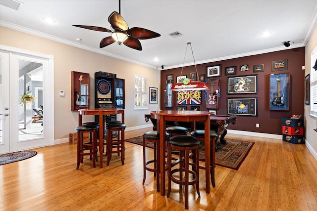 dining area featuring visible vents, crown molding, a dry bar, light wood-type flooring, and french doors