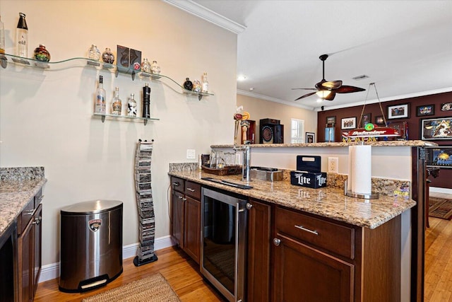 kitchen with crown molding, light hardwood / wood-style flooring, ceiling fan, kitchen peninsula, and beverage cooler