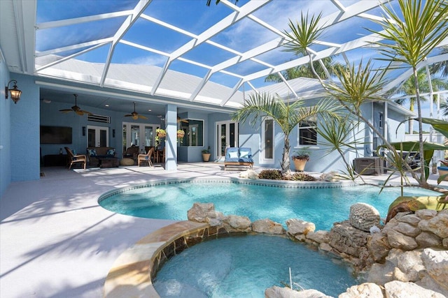 view of swimming pool featuring a ceiling fan, a pool with connected hot tub, a patio, french doors, and glass enclosure