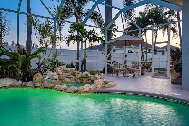 pool at dusk with a patio and glass enclosure