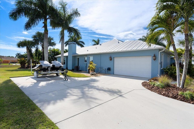 ranch-style home with stucco siding, driveway, a front lawn, an attached garage, and metal roof