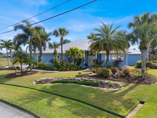 ranch-style house featuring metal roof, a front lawn, and stucco siding