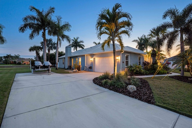 view of front of house featuring a front lawn, an attached garage, driveway, and stucco siding