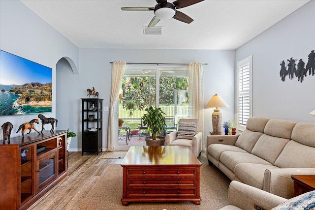 living room featuring ceiling fan, plenty of natural light, hardwood / wood-style floors, and a textured ceiling