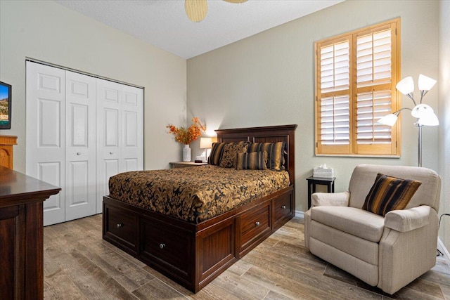 bedroom with ceiling fan, a closet, and light hardwood / wood-style flooring