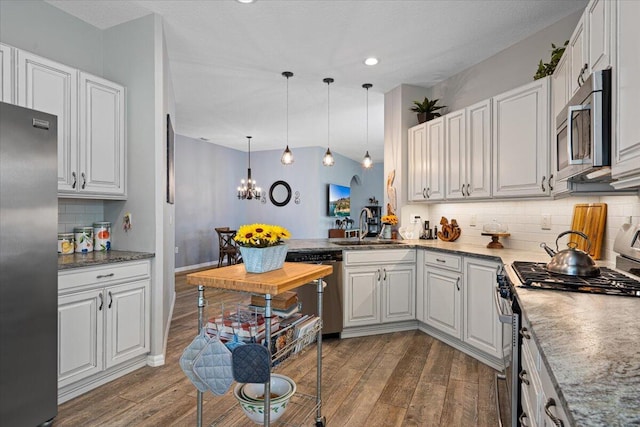 kitchen with stainless steel appliances, hanging light fixtures, and white cabinets