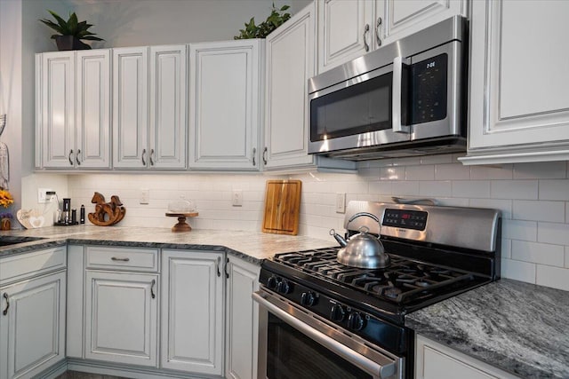 kitchen featuring tasteful backsplash, appliances with stainless steel finishes, white cabinets, and light stone counters