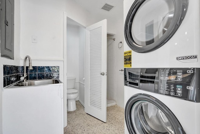 clothes washing area featuring stacked washing maching and dryer, sink, and electric panel