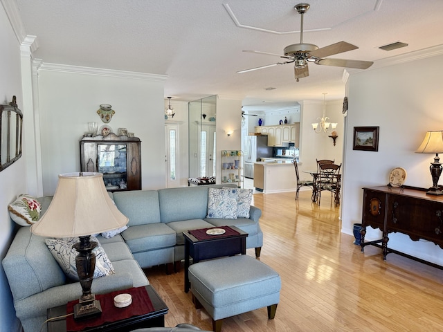 living area featuring light wood finished floors, visible vents, ornamental molding, and ceiling fan