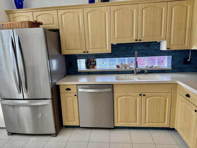 kitchen with a sink, light tile patterned floors, appliances with stainless steel finishes, and light brown cabinets
