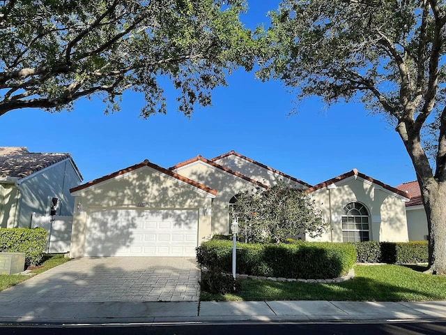 view of front facade with an attached garage, stucco siding, decorative driveway, and a tiled roof