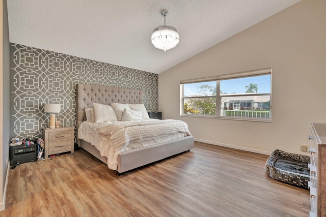 bedroom featuring vaulted ceiling, an accent wall, light wood finished floors, and baseboards