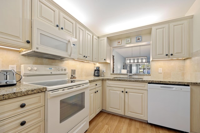 kitchen featuring sink, light stone counters, light hardwood / wood-style flooring, white appliances, and cream cabinets