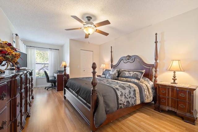 bedroom with ceiling fan, light hardwood / wood-style floors, a closet, and a textured ceiling