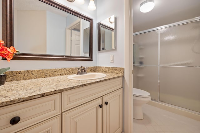 bathroom featuring vanity, a shower with door, and toilet