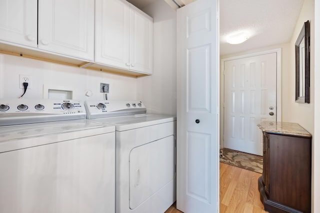 laundry area featuring cabinets, separate washer and dryer, a textured ceiling, and light hardwood / wood-style floors