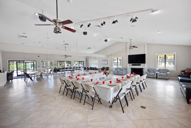 tiled dining space with ceiling fan, high vaulted ceiling, and a textured ceiling