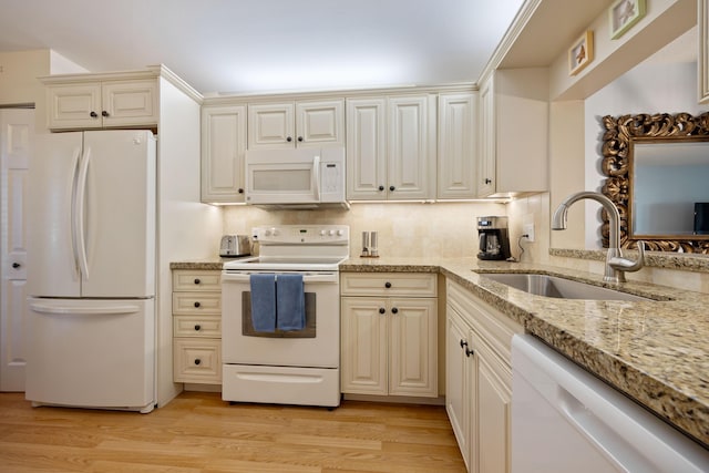 kitchen featuring sink, white appliances, backsplash, light hardwood / wood-style floors, and cream cabinetry