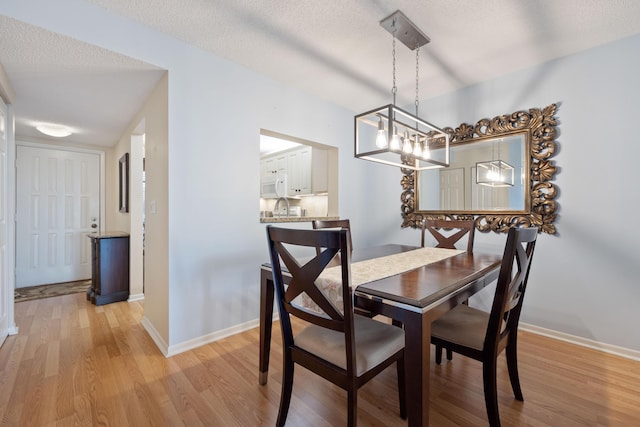 dining space with light hardwood / wood-style floors and a textured ceiling