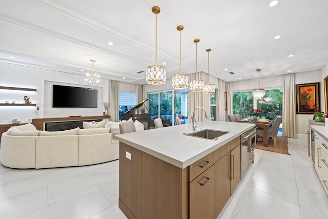 kitchen featuring an island with sink, decorative light fixtures, dishwashing machine, and sink