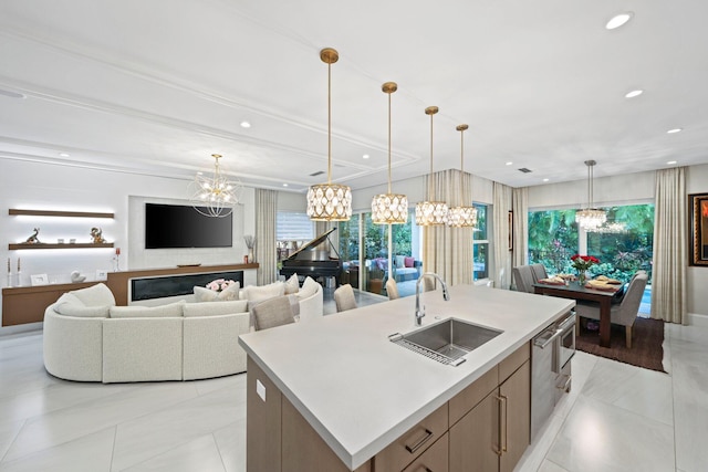 kitchen with an island with sink, sink, pendant lighting, and a notable chandelier