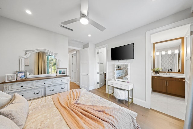 bedroom featuring ceiling fan, connected bathroom, sink, and light wood-type flooring