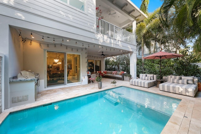 view of swimming pool with an outdoor living space, a patio, ceiling fan, and an outdoor kitchen