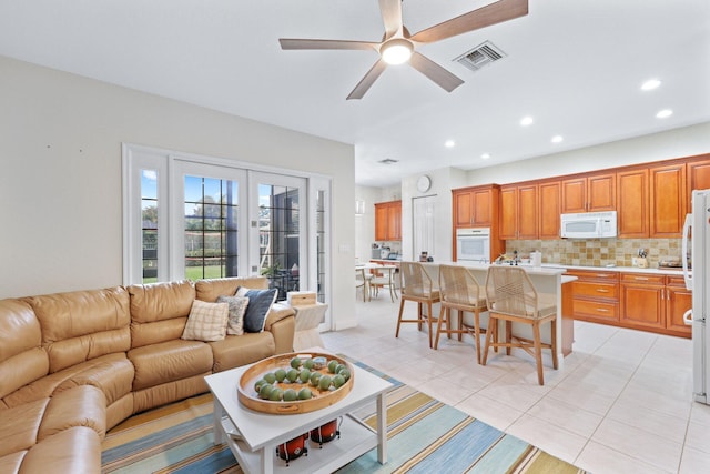 tiled living room with ceiling fan and french doors