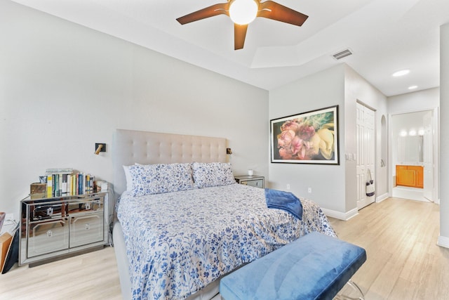 bedroom featuring ceiling fan, connected bathroom, and light hardwood / wood-style flooring