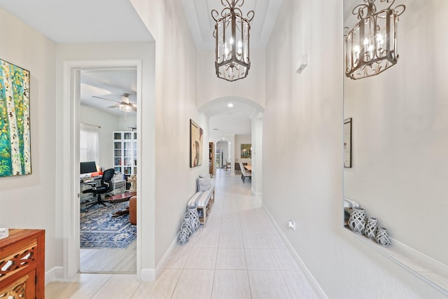 tiled foyer featuring ceiling fan with notable chandelier