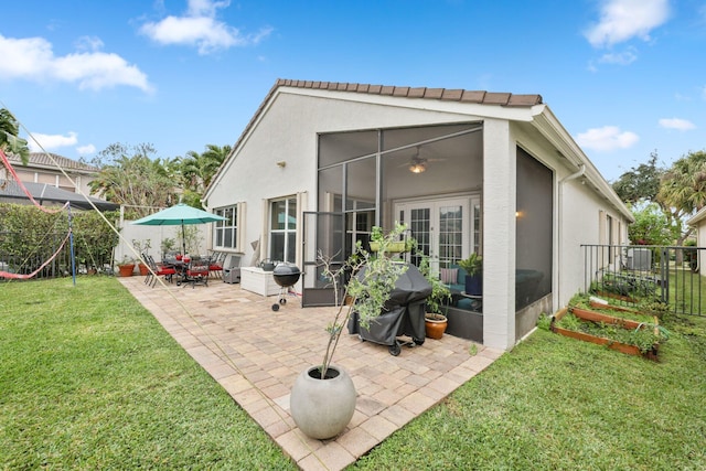 rear view of property featuring ceiling fan, a yard, a sunroom, and a patio area