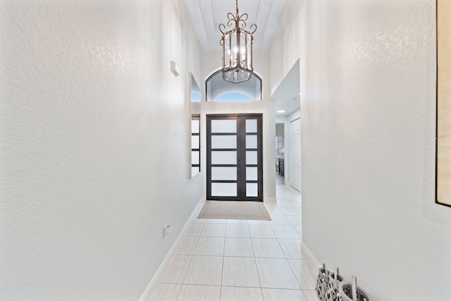 tiled foyer entrance with a towering ceiling and a chandelier