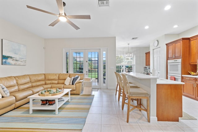 tiled living room featuring ceiling fan and french doors