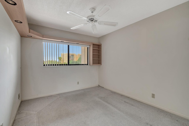 carpeted spare room featuring ceiling fan, a textured ceiling, and baseboards