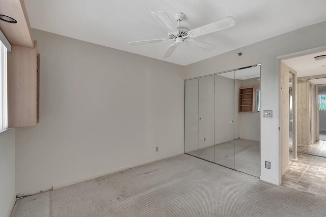 unfurnished bedroom featuring baseboards, carpet, a ceiling fan, and a closet