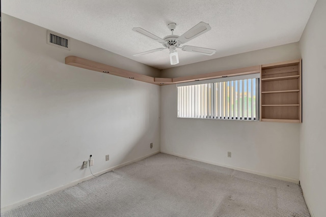 carpeted empty room with a ceiling fan, baseboards, visible vents, and a textured ceiling