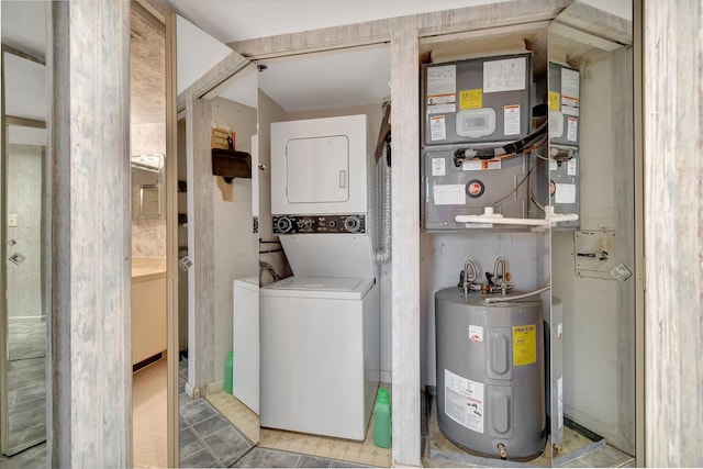 laundry area featuring laundry area, water heater, stacked washer / dryer, and tile patterned floors