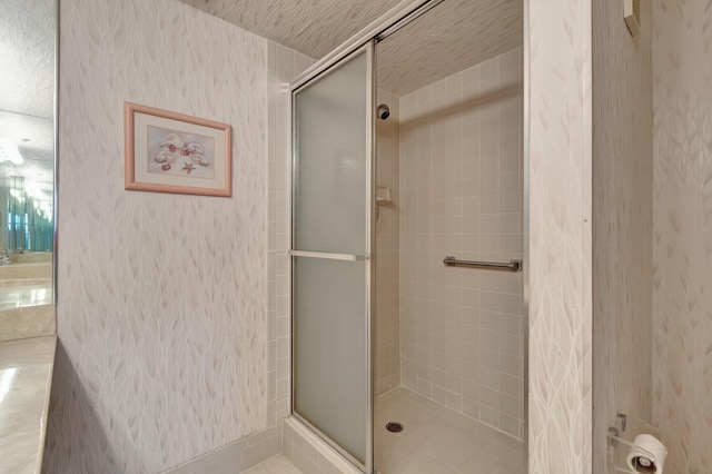 bathroom featuring a stall shower and wallpapered walls