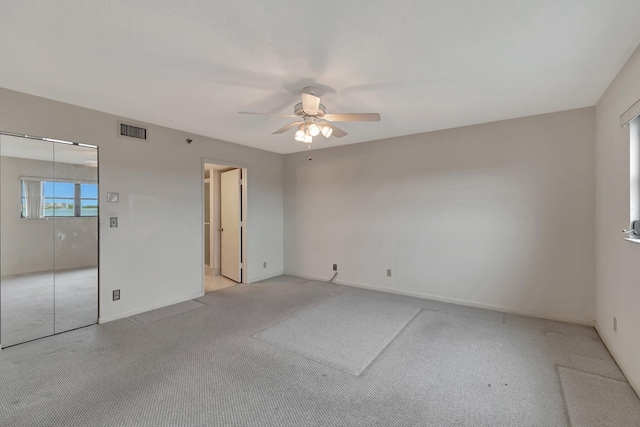 unfurnished bedroom with baseboards, light colored carpet, visible vents, and a ceiling fan